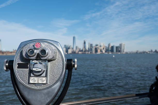 istock Tower viewer binoculars in foreground blurred New York City skyline in background overlooking Hudson River and the New York Harbor on a bright sunny day.  Blue skies and wispy clouds over Manhattan. 643480590