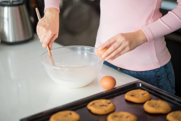 istock Young woman preparing dough and baking chocolate chip cookies 643484042