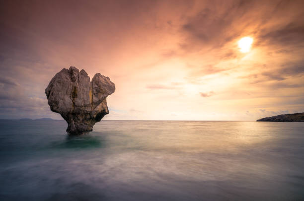 istock Lonely rock sculpture in the sea under sunset. 643484918