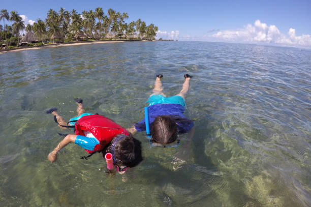 Mother and child snorkeling over a coral reef Fiji Mother and child girl snorkeling over a coral reef in a tropical resort on Vanua Levu Island, Fiji. Real people copy space scuba diving family stock pictures, royalty-free photos & images