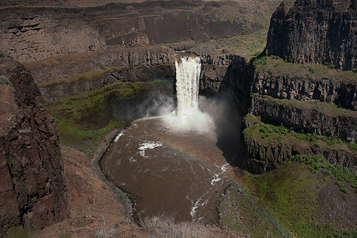 View from a vantage point of Palouse Falls in LaCrosse, Washington State, USA. A small rainbow has formed in the mist of the falls at the bottom.