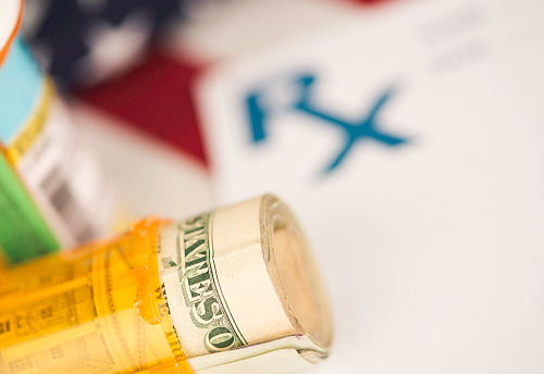 Cost of American prescription drugs. RX form with pill bottle, American flag and US currency