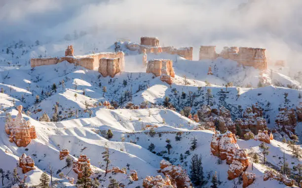 A ridge of hoodoos covered in snow about to be swallowed by the fog in Bryce Canyon National Park, Utah