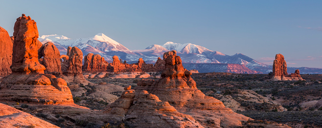 Warm late afternoon sunlight sidelights the rock formations in the Garden of Eden adn the Windows Sections, with the LaSal Mountains behind in Arches National Park, Utah