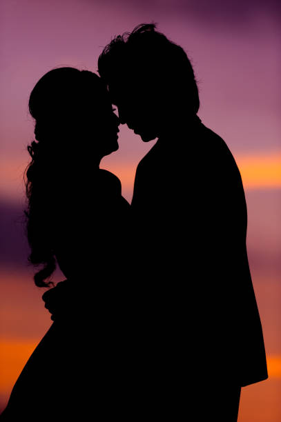 silhouette of embracing asian bride and groom at sunset - silhouette kissing park sunset imagens e fotografias de stock