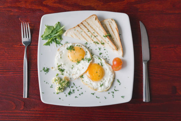 istock Fried eggs on white plate with green and tomato cherry - breakfast, top view 643537146