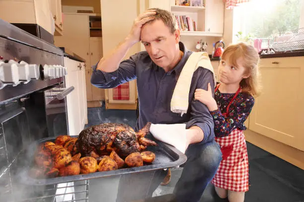 a mature man pulls the chicken or turkey out of the oven only to find it burnt and ruined. His little daughter consoles him.
