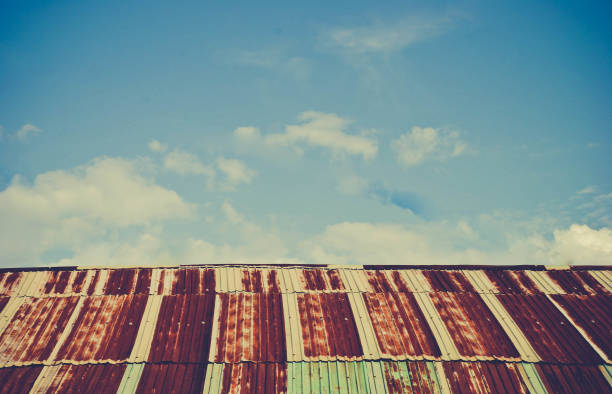 stary zardzewiały i wyblakły dach chaty z estakady stalowej quonset przed błękitnym niebem z chmurami puchowymi vintage tone - quonset zdjęcia i obrazy z banku zdjęć