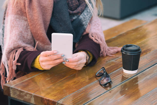 istock Woman drinking coffee and using her cellphone outdoors. 643553842