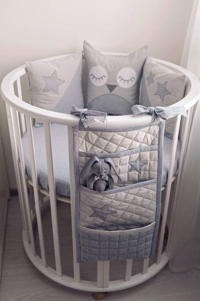 istock round white baby bed with gray pillows 643553978