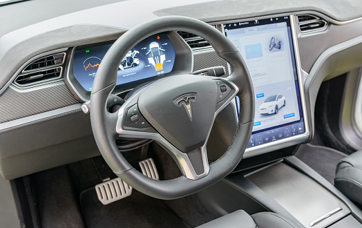 Interior on a Tesla Model X all-electric crossover SUV with large electronic touch screens on the dashboard and luxurious leather seats and aluminium and carbon details. The Tesla Model X is a full-sized all-electric crossover SUV made by Tesla Motors that uses falcon wing doors. The car is on display during the 2016 Classic Days at Schloss Dyck.