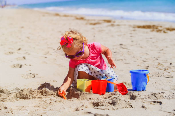 istock cute little girl play with sand on beach 643582440