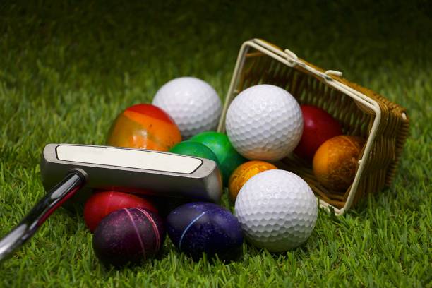 Golf balls  and putter with basket of Easter eggs on green background Golf ball and putter with basket of Easter eggs are on green grass. easter egg photos stock pictures, royalty-free photos & images