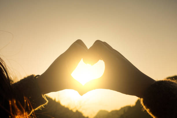 istock Woman making a heart shape at sunset 643620518