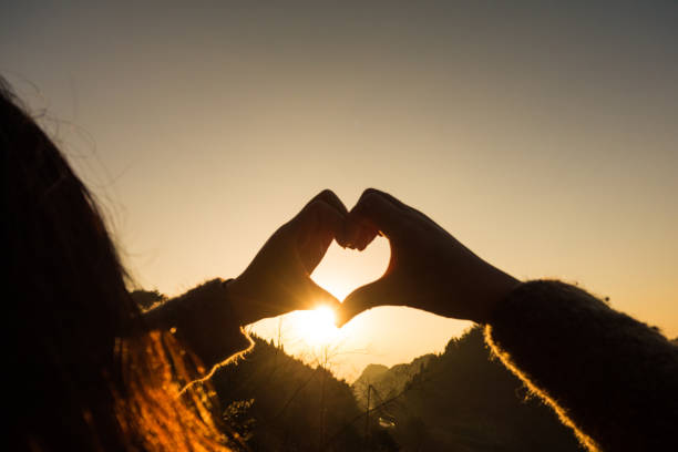 istock Woman making a heart shape at sunset 643620552