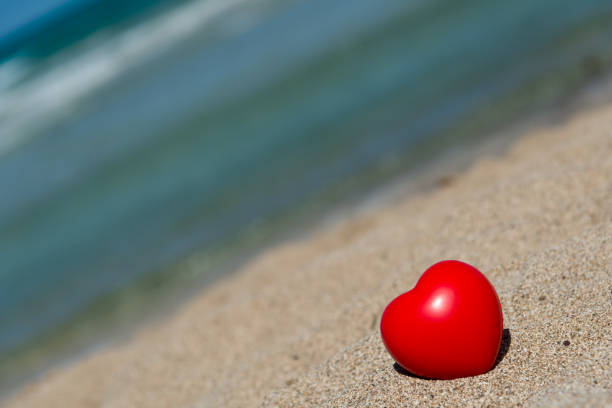 istock red heart in sand on beach - holiday love 643623018