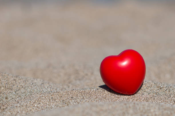 istock red heart in sand on beach - holiday love 643623296