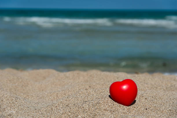 istock red heart in sand on beach - holiday love 643623552