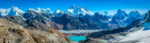 Panoramic view from the Renjo La over Gokyo Lake and Sherpa village to the Everest range high in the Sagarmatha National Park of the Nepalese Himalayas, from the iconic summits of Pumori (7161m), Mt. Everest (8848m), Nuptse (7861m), Lhotse (8516m) and Makalu (8481m) to the dramatic pinnacles of Tawoche (6542m) and Cholatse (6440m) under deep blue high altitude skies.