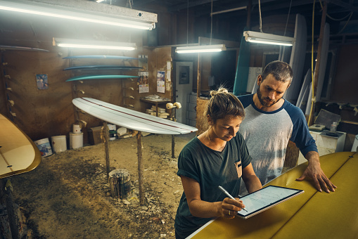 Cropped shot of two young artisans working in their surfboard workshop