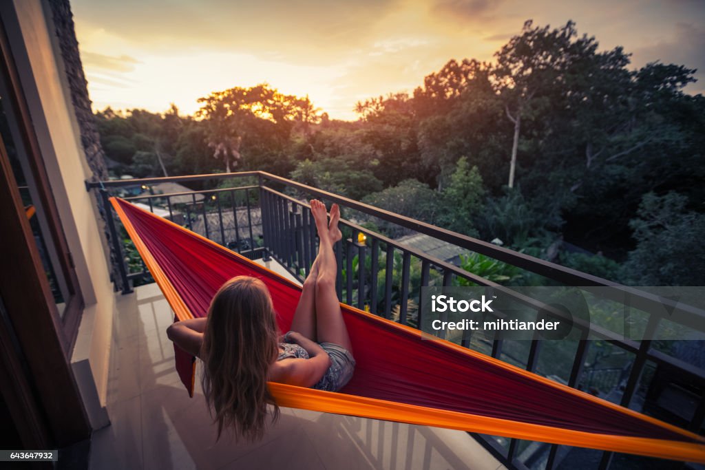 Woman in the hammock Young woman enjoys sunset relaxing in the hammock on the balcony Balcony Stock Photo