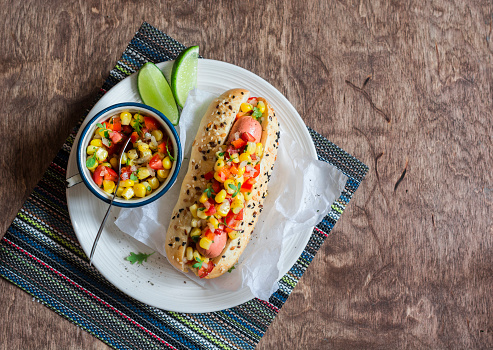 Mexican street style hot dog on wooden background, top view.