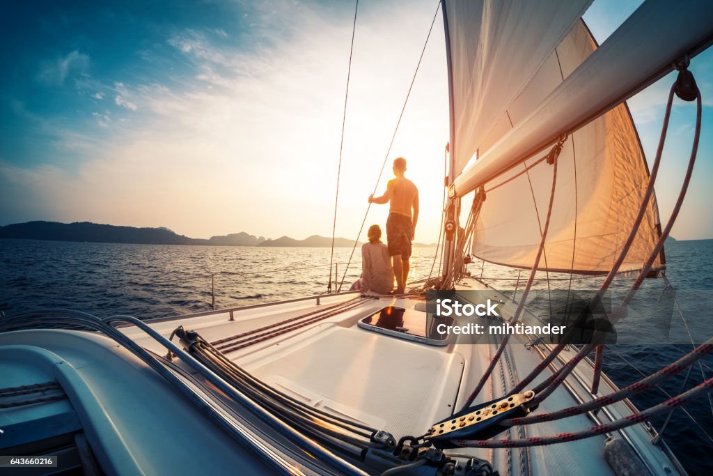 Couple de profiter des coucher de soleil depuis le bateau à voile - Photo de Bateau à voile libre de droits