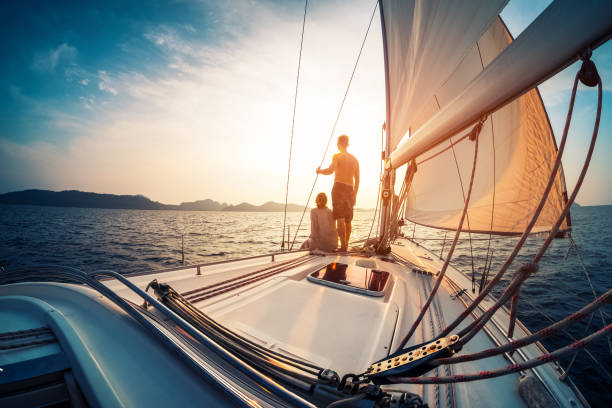 Couple enjoying sunset from the sail boat Couple enjoying sunset from the deck of the sailing boat moving in a sea aquatic sport photos stock pictures, royalty-free photos & images