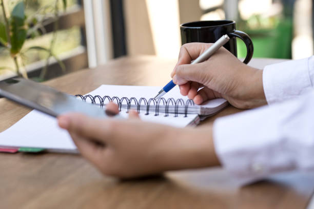 istock Businesswoman using smart phone and writing in diary 643663268
