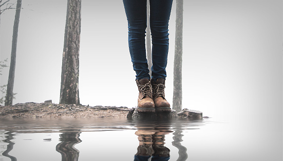 Standing thin young man's legs reflected in bulbous, circular bokeh of rainwater trapped on the cement floor. in the lonely night