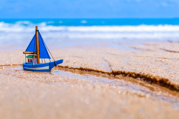 istock Miniature toy sailboat on the beach 643673680