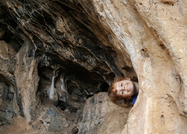 istock 6 year old kid look out from cave 643678724