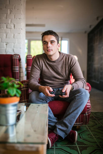 istock Handsome man playing video game at home 643687846