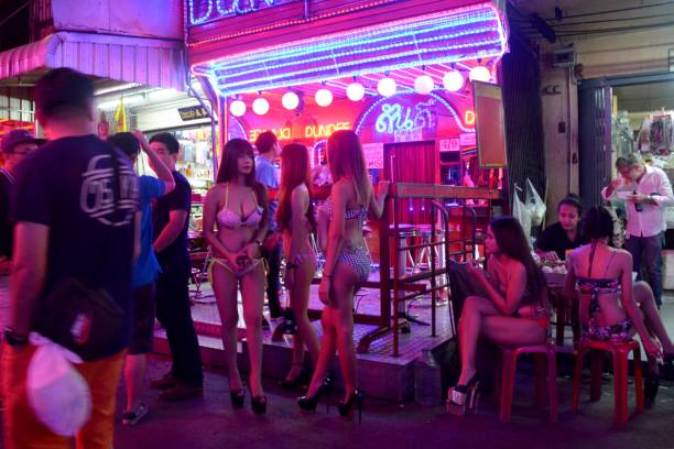 Sexy girls on Soi Cowboy strip, Bangkok, Thailand Tourists and Thai ladies dressed in sexy dresses, outside a Go-go Bar along Soi Cowboy, a short walking street of bars and strip clubs in the Asok-Sukhumvit district. strip club stock pictures, royalty-free photos & images