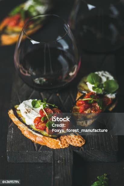 Brushetta With Eggplant Tomatoes Garlic Creamcheese Arugula Glass Of Wine Stock Photo - Download Image Now