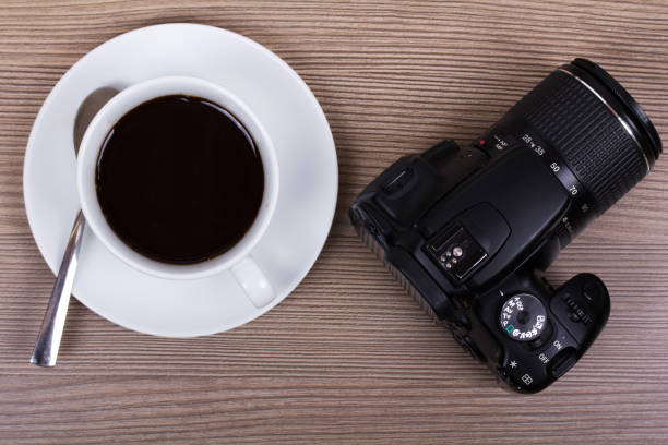 istock Coffee cup and camera on a wooden surface 643697624