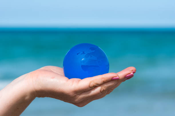 blue earth globe glass ball on hand at beach
