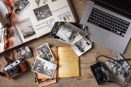 Moscow, Russian Federation - February 20, 2017: Old family photos on wooden background. Vintage pictures, camera, notepad and modern notebook. Flat lay close up view. Presented to me by my family.