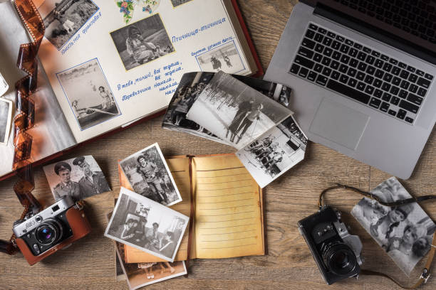 Old family photos on wooden background Moscow, Russian Federation - February 20, 2017: Old family photos on wooden background. Vintage pictures, camera, notepad and modern notebook. Flat lay close up view. Presented to me by my family. input device photos stock pictures, royalty-free photos & images