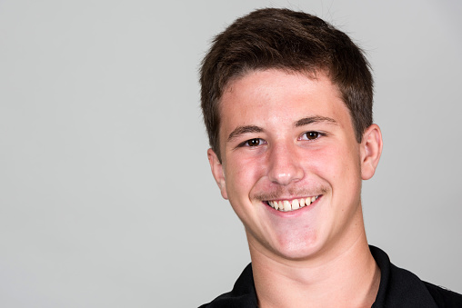 Smiling caucasian teenage boy looking at the camera on gray background