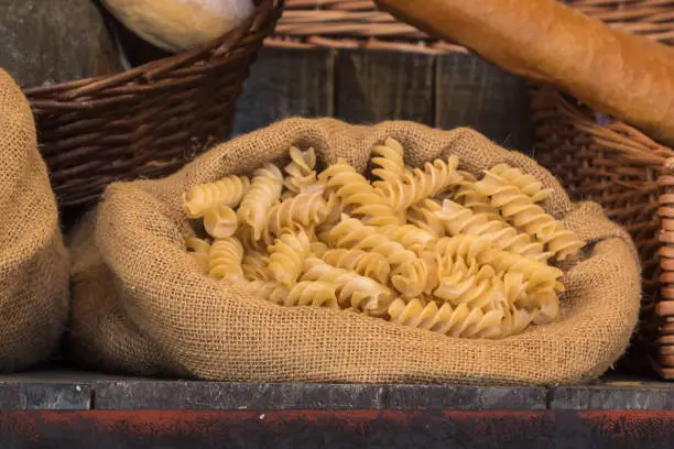 Uncooked Italian Pasta in Jute Bag on Wooden Table