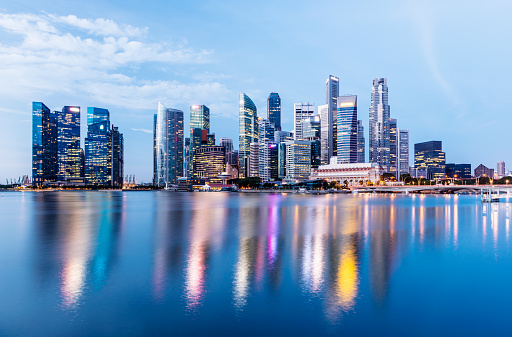 The Singapore Downtown City and Marina Bay Business District Skyline at twilight with reflection in the still water.