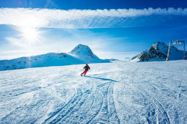 Skier skiing down the slope of ski resort on sunny winter day.