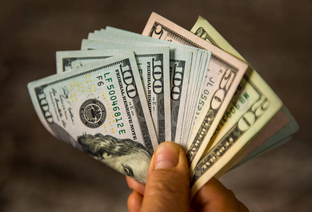 nierozpoznawalny dojrzały mężczyzna posiadający banknoty w dolarach amerykańskich - stack heap currency one hundred dollar bill zdjęcia i obrazy z banku zdjęć