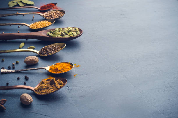 Variety of herbs and spices on slate background.