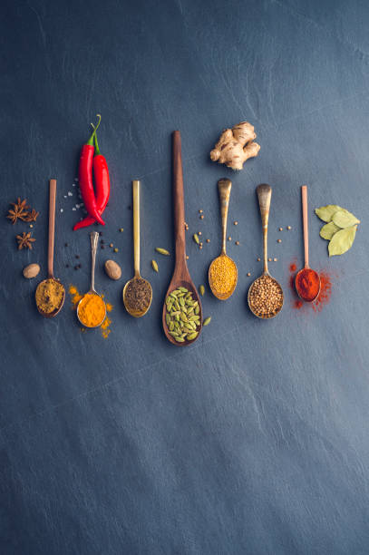 Variety of herbs and spices on slate background. Variety of herbs and spices on slate background. Many are held on metal and wooden spoons. There is also a chilli pepper. indian condiments stock pictures, royalty-free photos & images