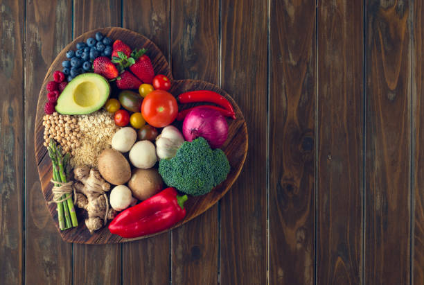 Healthy food on a heart shape cutting board Healthy food on a heart shape cutting board. Love of food concept with fruit, vegetables, grains and high fibre foods. Rustic wood textures antioxidant stock pictures, royalty-free photos & images