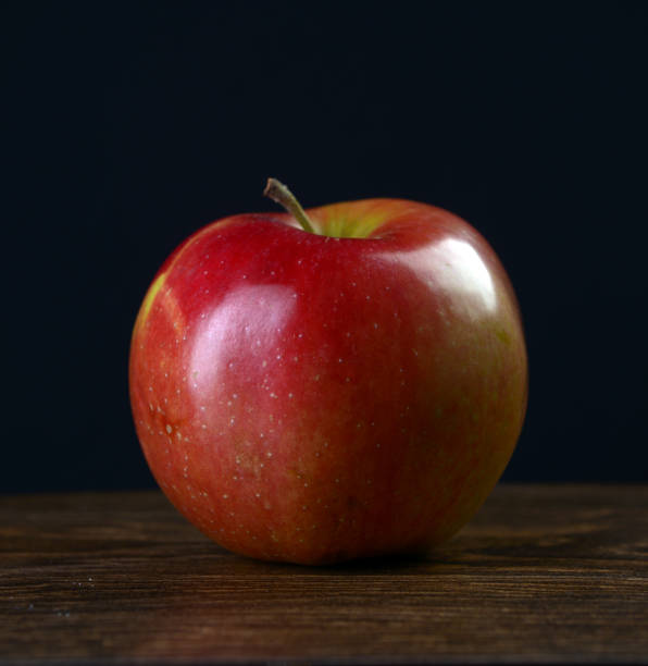istock Ripe red apple on a dark wooden table on a black background 643768192