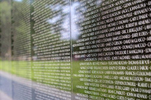 A close up  of the names of dead solidiers on the reflective black marble on the Vietnam Memorial on the Mall in Washington DC. Each name is in chronological order of their death.