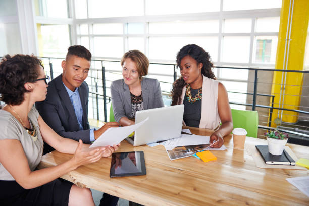 team of successful business people having a meeting in executive sunlit office Candid photo of a corporate businesspeople group discussing strategies in professionnal indoors setting. shareholders meeting stock pictures, royalty-free photos & images